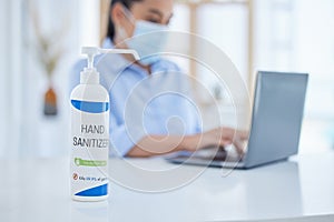 Hand sanitizer, covid and business woman typing on a laptop at desk in her office with face mask. Hygiene, technology