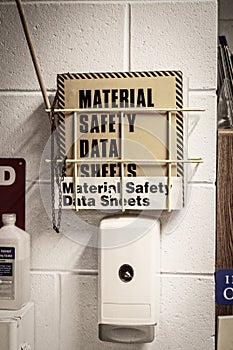 Hand sanitizer and msds safety data sheets mounted on concrete block wall in work place