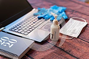 Hand sanitizer work from home kit on wooden office desk with computer and face mask, a solution against the spread of corona virus photo