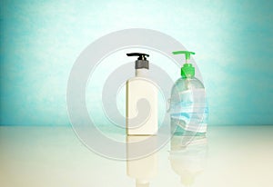 Hand sanitizers side by side where one is covered by face mask over blue background. Conceptual of keeping sanitized hands and