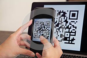 Hand scanning QR code to pay for online shopping