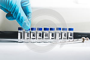 Hand of the scientist pick up the vial of sample solution to analyze by Liquid Chromatography mass spectrometry LC-MS instrument