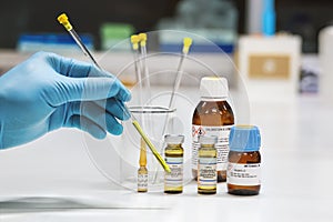 Hand of the scientist shows yellow sample solution and NMR solvent glass bottles