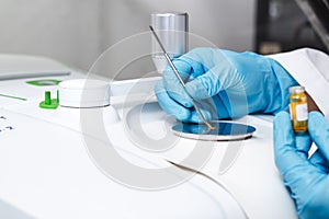 Hand of the scientist using a stainless spatula to scoop sample solid from vial to sample analysis and chemical characterization