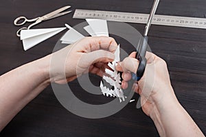 Hand with scissors cut snowflake from paper