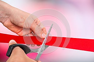 Hand with scissors cutting red ribbon - opening ceremony