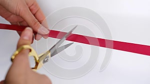 Hand with scissors cutting red ribbon opening ceremony concept. Isolated on white background