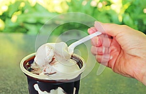Hand Scooping Chocolate Sauced Vanilla Soft Serve Ice Cream with Spoon