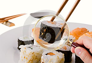 Hand Scrutinizing Sushi Served In Plate Through Magnifying Glass