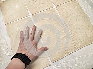 Hand pressing dough on a floured surface to prepare for baking in a kitchen setting during daytime photo