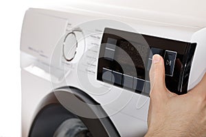 The hand select settings for laundry on modern digital display. Close-up view of automatic washing machine with touch screen on