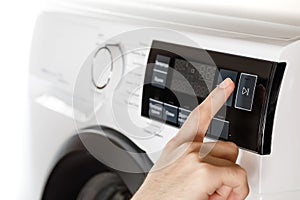 The hand select settings for laundry on modern digital display. Close-up view of automatic washing machine with touch screen on