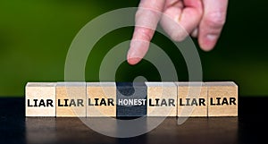Hand selects the cube with the word 'honest' instead of cubes with the word 'liar'.