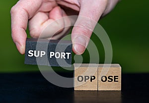 Hand selects wooden cubes with the word support instead of cubes with the word oppose