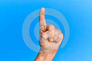 Hand of senior hispanic man over blue isolated background counting number one using index finger, showing idea and understanding