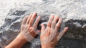 Hand of senior woman climbs a rock and slides down, the concept of hopelessness, failure and tiredness and problems of the elderly