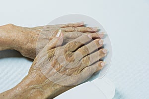 Hand of senior woman with lotion bottle on white table