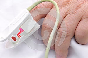 Hand of seriously ill with oxygen saturation sensor.