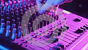 Hand Settings Volume Level Controls on Mixing Console Faders Neon Light Close-Up