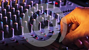 Hand Settings Volume Level Controls on Mixing Console Faders Neon Light Close-Up