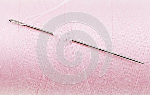 Hand sewing needle in pink thread bobbin
