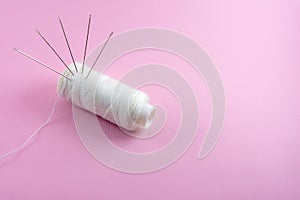 hand sewing tools, needle and white thread isolated on pink background