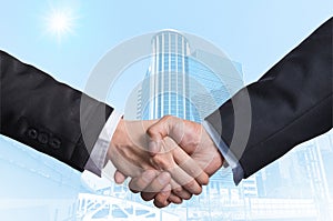 Hand shake between a businessman on Modern business building glass area background