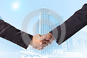 Hand shake between a businessman on Modern business building glass area background