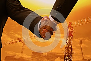 Hand shake between businessman,successfully negotiated an achieved excellent commercial cooperation,sunset sky and construction