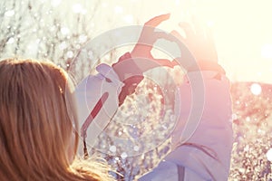 Hand shaped heart against sky background