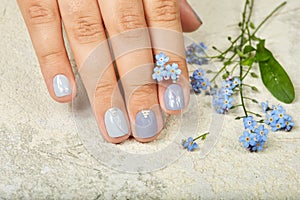 Hand with short manicured nails colored with gray nail polish