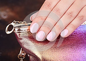Hand with short manicured nails colored with pink nail polish