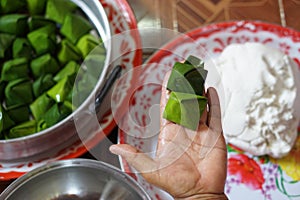 Hand show wrapped dough with green banana leaf for cooking Thai traditional dessert.