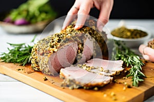 hand showcasing sliced herb crusted pork loin