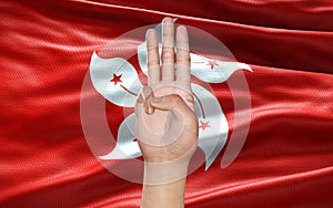 Hand showing 3 fingers, a political symbol, on Hong Kong flag background, as an act of resistance against Military Government