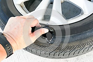 Hand showing flat ruptured damaged tire wheel with rim