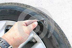 Hand showing flat ruptured damaged tire wheel with rim