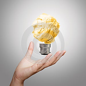 Hand showing light bulb crumpled paper
