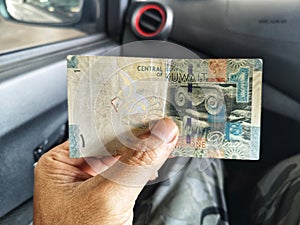 Hand showing One Dinar Central Bank of Kuwait money with blur background