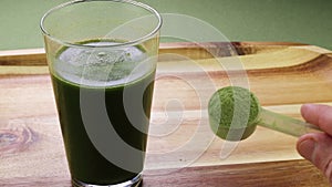 Hand Showing Organic Celery Powder Near a Celery and Aloe Drink