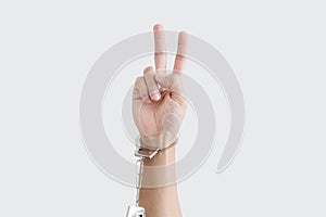 Hand showing peace hand sign, with handcuff,  on white background