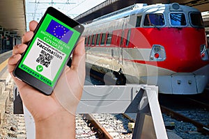 Hand showing valid european digital vaccination certificate on smartphone display at train station