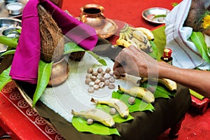 Hand showring rice gains on hindu pooja arrangements containing betel leafs, coconut & x28;pooja kalash& x29;, rice and areca nuts