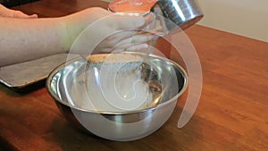 Hand sifting flour into bowl