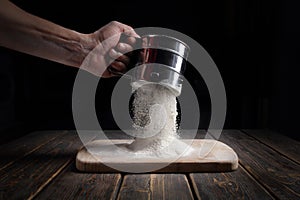 Hand sifts the flour through a sieve. photo