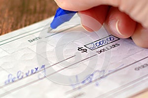 Hand sign a bank check on wooden table background, Blank bank cheque, Prepare writing a check, closeup