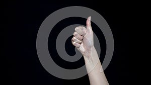 Hand sign meaning like. Close-up of thumb sign up. Good hand gesture. Black isolated background