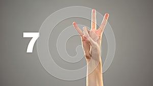 Hand signing 7 in asl, number on background, sign language tutorial for deaf