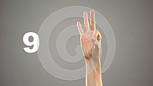 Hand signing 9 in asl, number on background, sign language tutorial for deaf