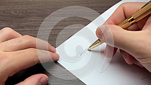 Hand signing writing yes on white paper isolated Caucasian approved verified authorized verified check gold pen brown table